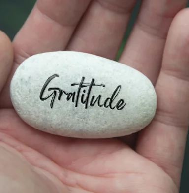 Hand holding Zen stone with Gratitude text engraved on the stone. Gratitude and peace concept.